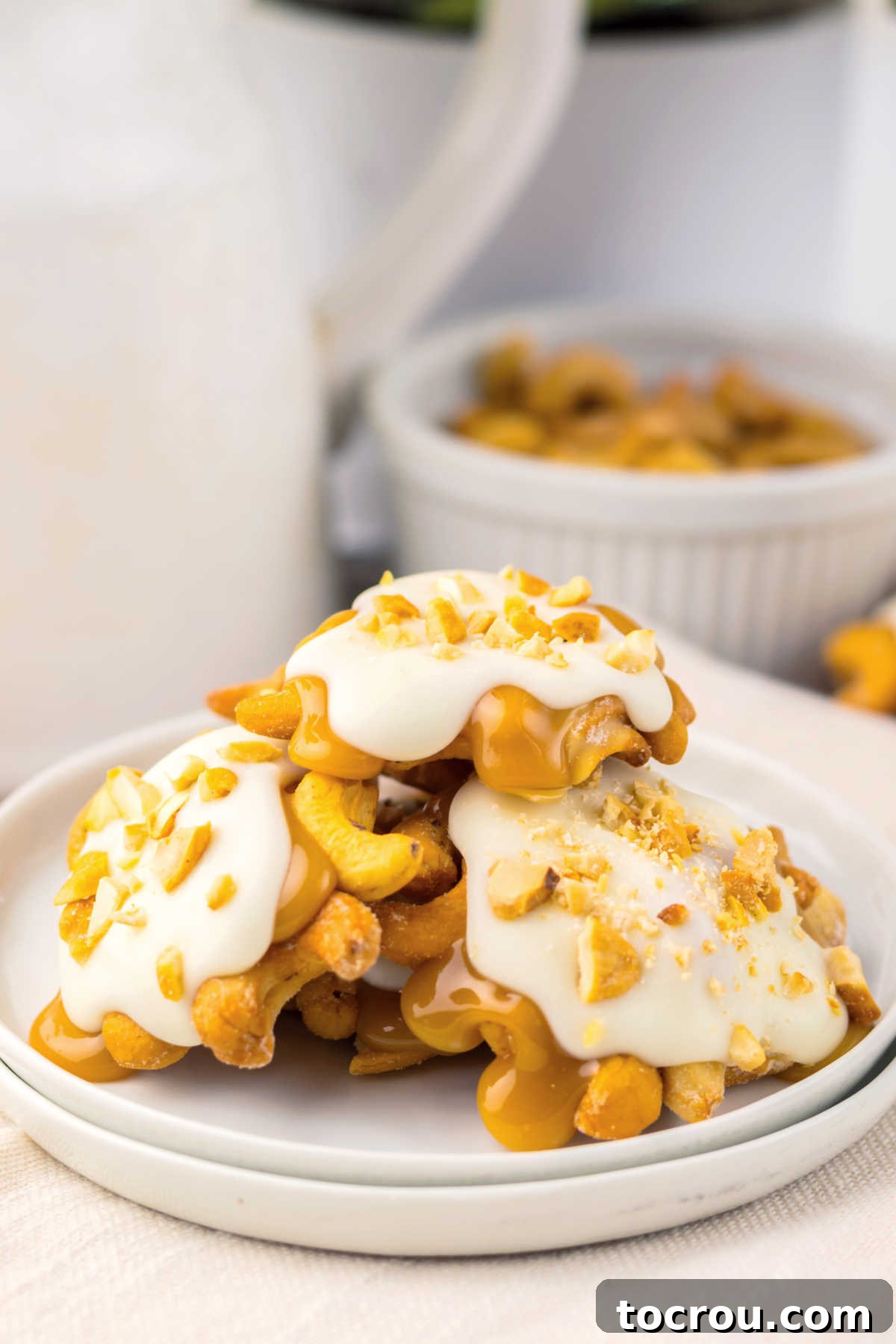 Pile of homemade white chocolate caramel cashew clusters on plate, ready to be served. 