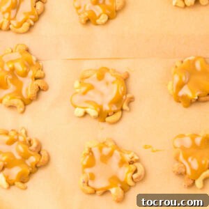 Dollops of caramel and cashews on parchment paper lined pan, waiting for their chocolate topping.