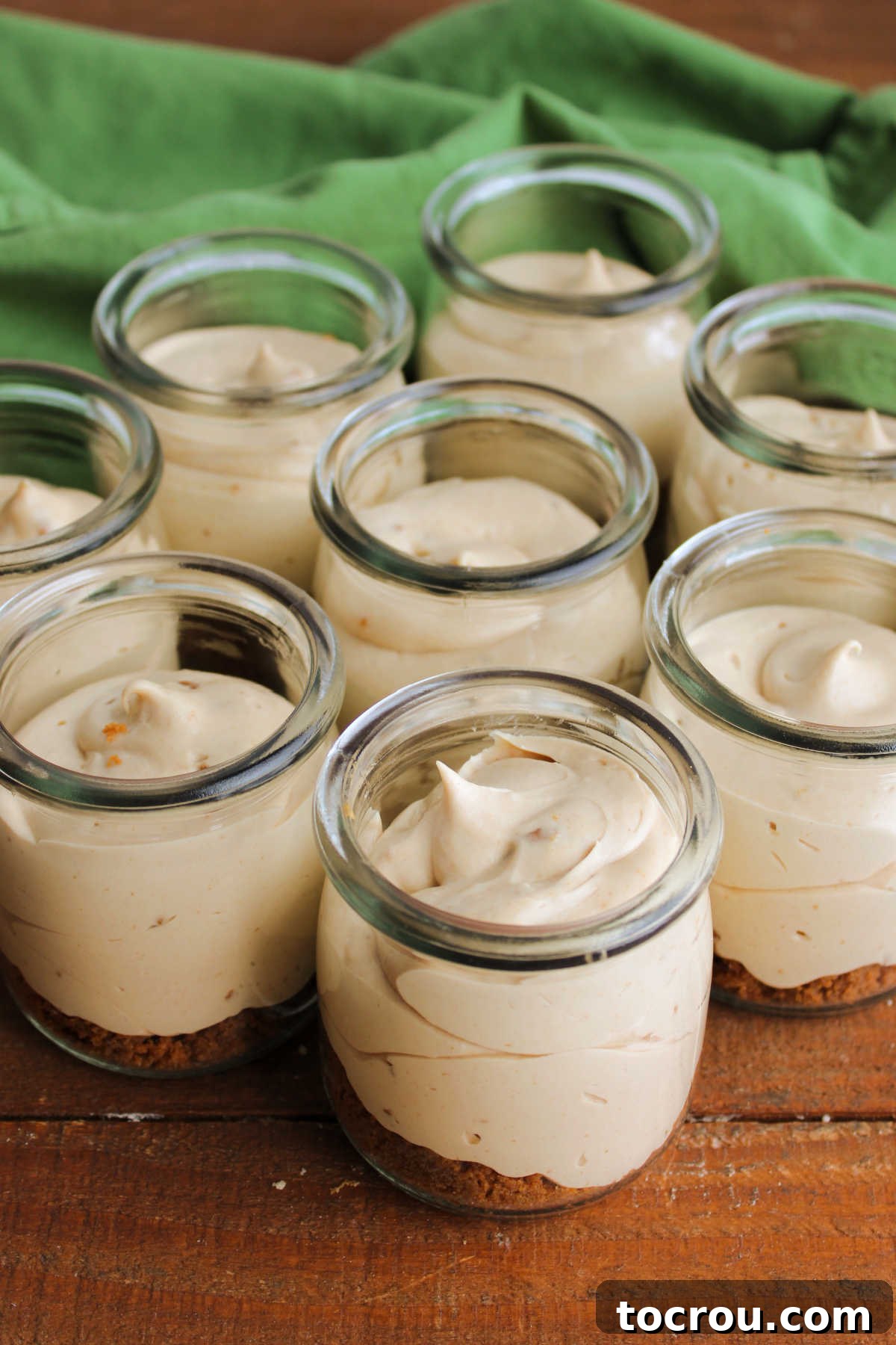 Overhead view of jars of no bake cookie butter cheesecake showcasing smooth fluffy texture with small bits of cookie throughout.