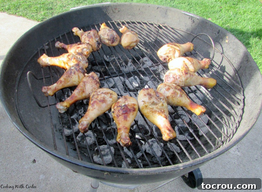 Chicken on Charcoal Grill Chicken drumsticks cooking on a charcoal grill, with smoke rising.