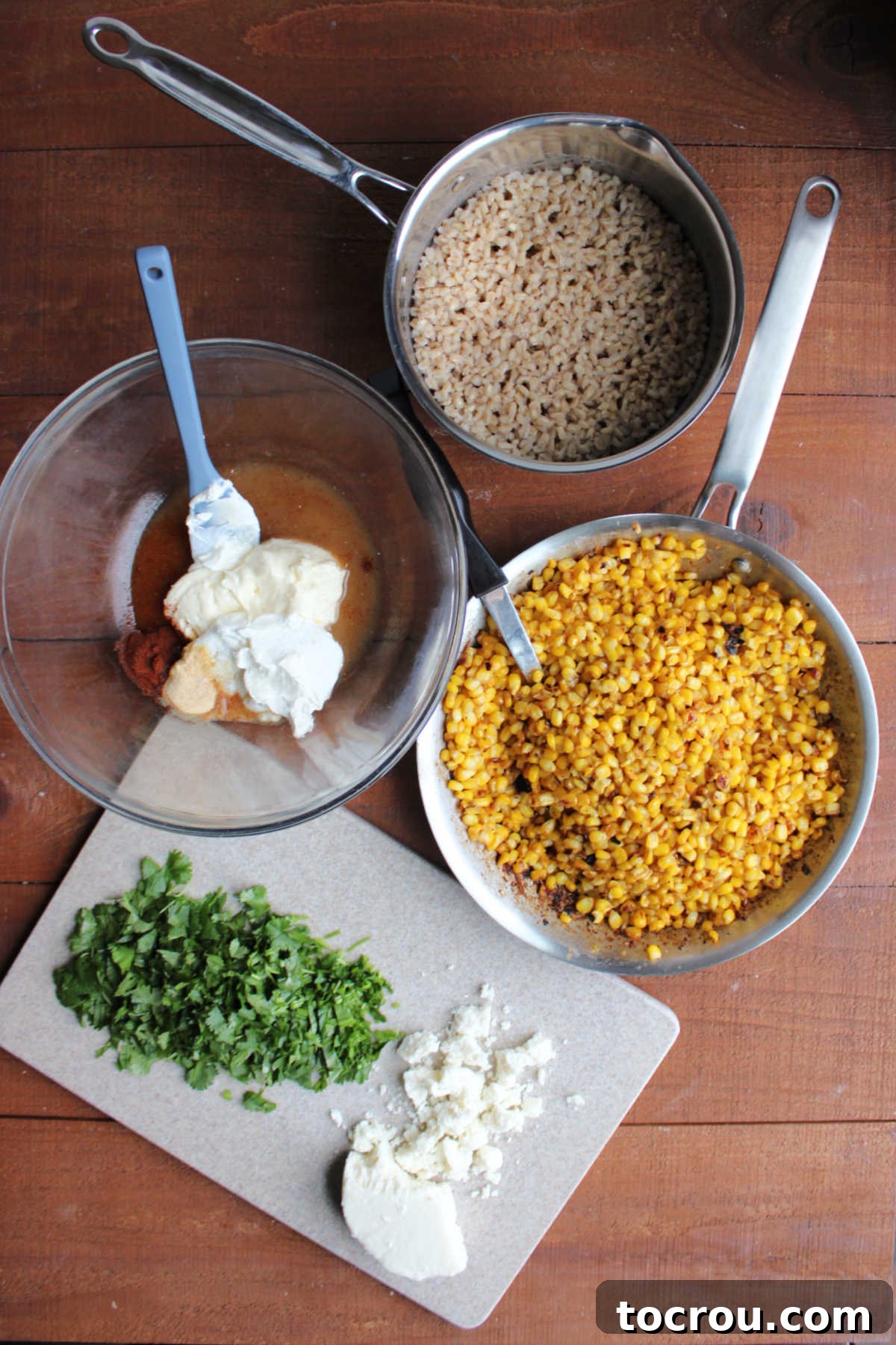 Ingredients for Mexican Street Corn Barley Salad Ingredients laid out for Mexican Street Corn Barley Salad: pearled barley, defrosted frozen corn, crumbled queso fresco, fresh cilantro, sliced green onions, sour cream, mayonnaise, lime juice, chili powder, garlic powder, and salt.