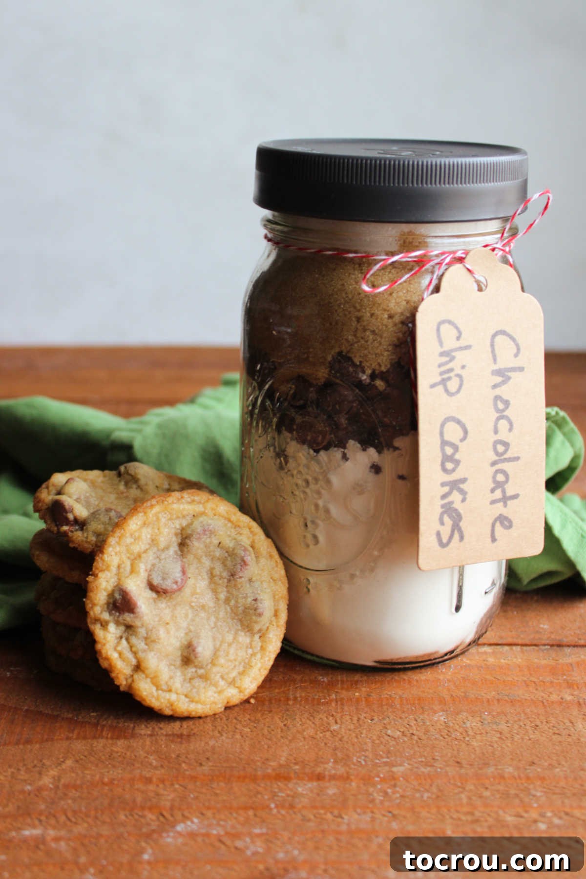 DIY Chocolate Chip Cookie Jar Mix 4 Jar of homemade chocolate chip cookie mix next to stack of cookies made from the mix.