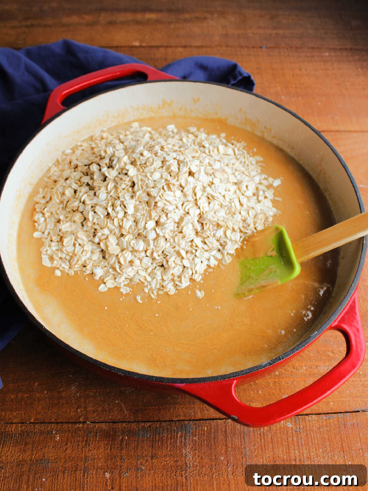 Hearty old-fashioned oats being carefully added to the warm, luscious peanut butter mixture in a saucepan.