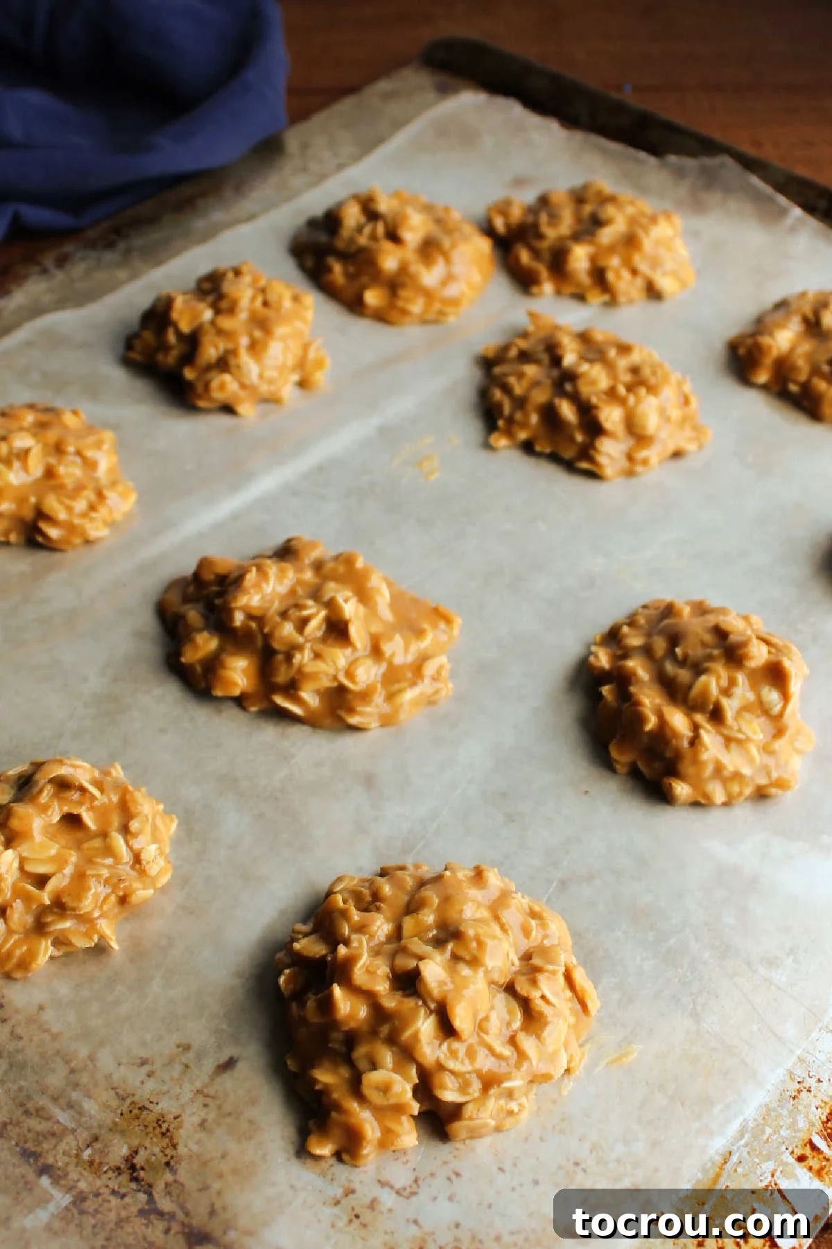 Freshly scooped peanut butter no-bake cookies neatly arranged on a wax paper-lined cookie sheet, cooling and setting.
