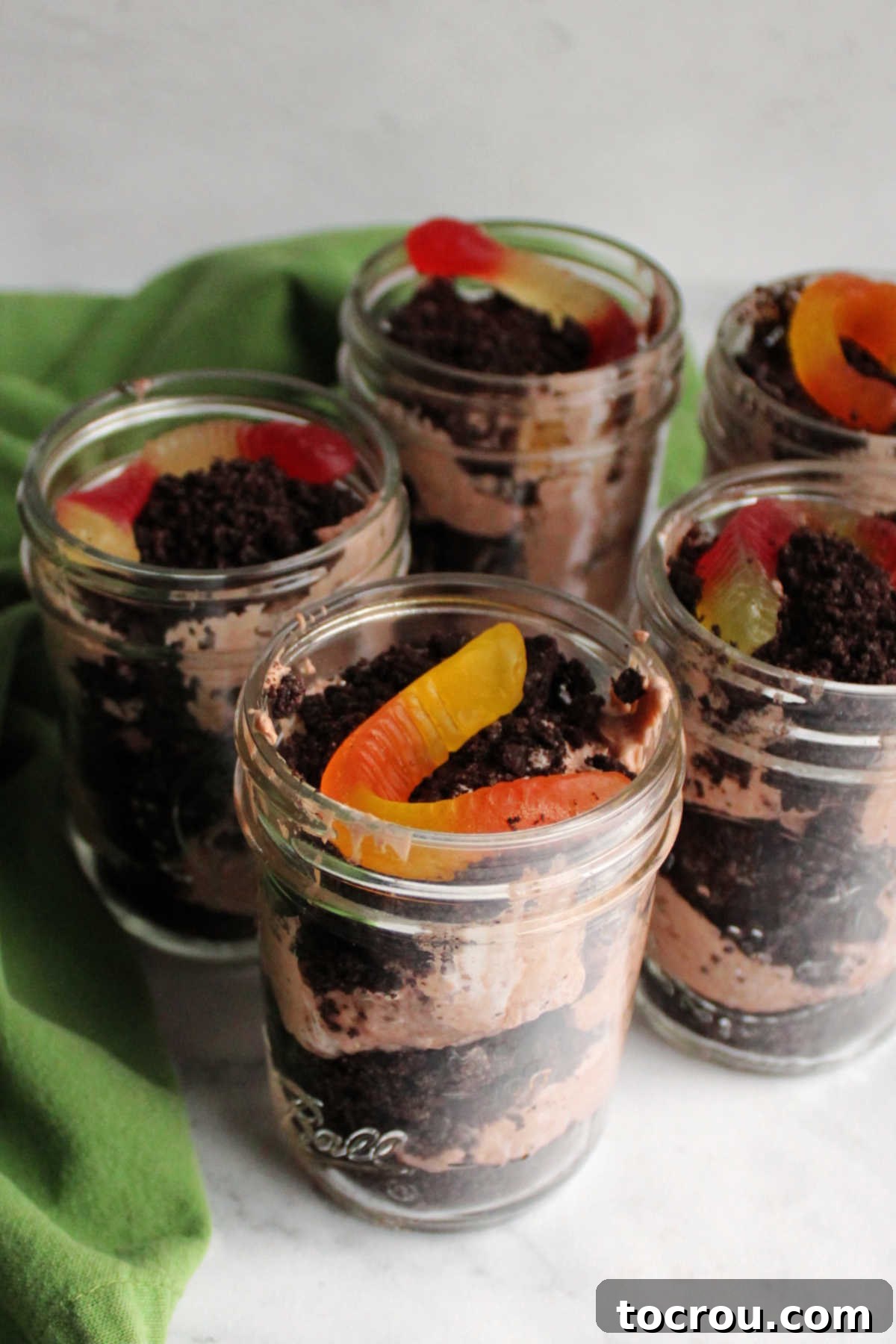 Dirt Pudding Jars with Gummy Worms Jars of dirt pudding with layers of Oreo crumbs, chocolate pudding mixture and a gummy worm on top.