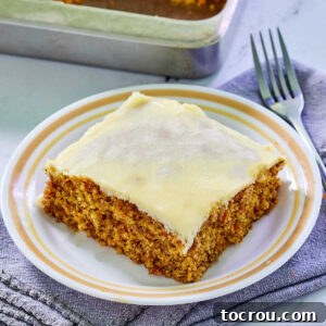 Pyrex plate with square piece of carrot cake topped with a layer of cream cheese frosting, ready to eat.