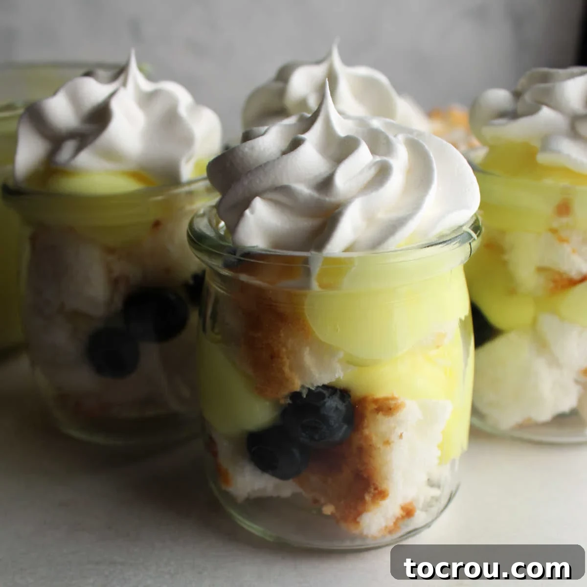 These gems are perfect for spring. Make as one big trifle or as individual trifles. Lemon. blueberries and angel food are a match made in heaven! Perfect for Easter and spring! Small glass jars filled with layers of angel food cake, blueberries, lemon yogurt mixture and topped with whipped cream. Perfect for spring and Easter.