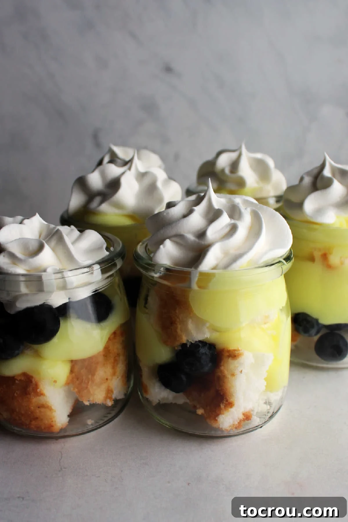 These gems are perfect for spring. Make as one big trifle or as individual trifles. Lemon. blueberries and angel food are a match made in heaven! Perfect for Easter and spring! Jars filled with lemon, blueberry and angel food cake trifle, garnished with fresh blueberries and lemon zest.