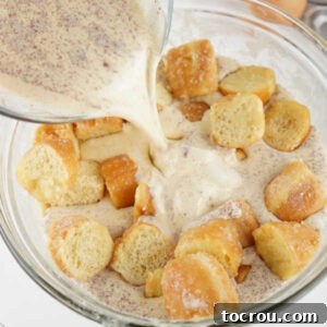 Pouring custard mixture over bowl of donut chunks.