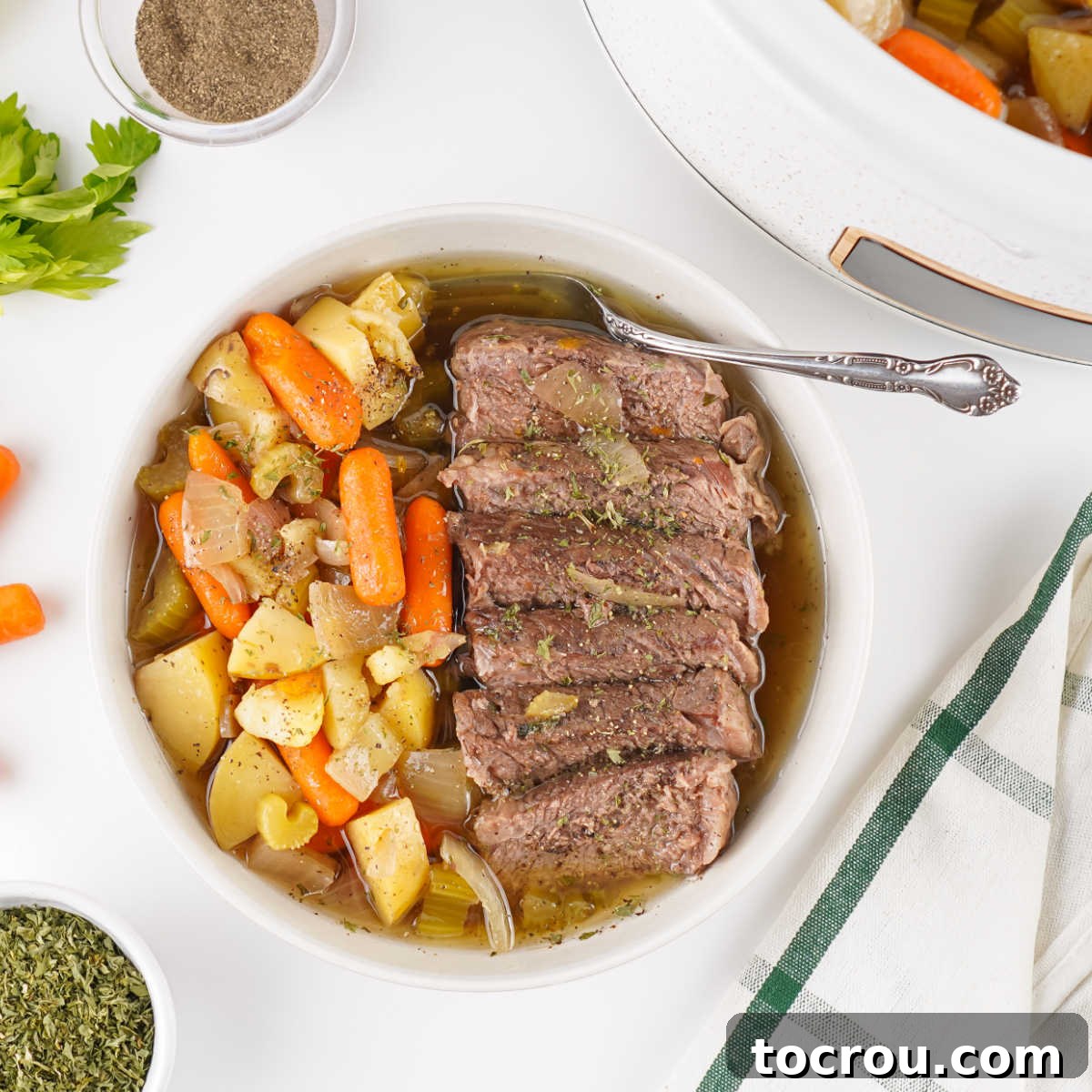 Plate with slices of roast beef served with cooked carrots, potatoes, celery, and onions in gravy.
