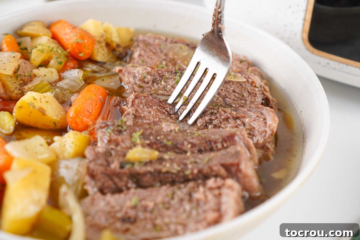 Fork getting a bite of tender roast beef from a bowl of slow cooker pot roast.