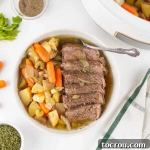 Plate with slices of roast beef served with cooked carrots, potatoes, celery, and onions in gravy.