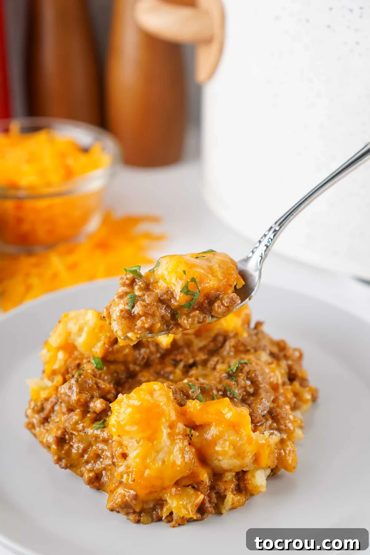 Fork getting a bite of tater tot casserole with taco meat and cheese. 