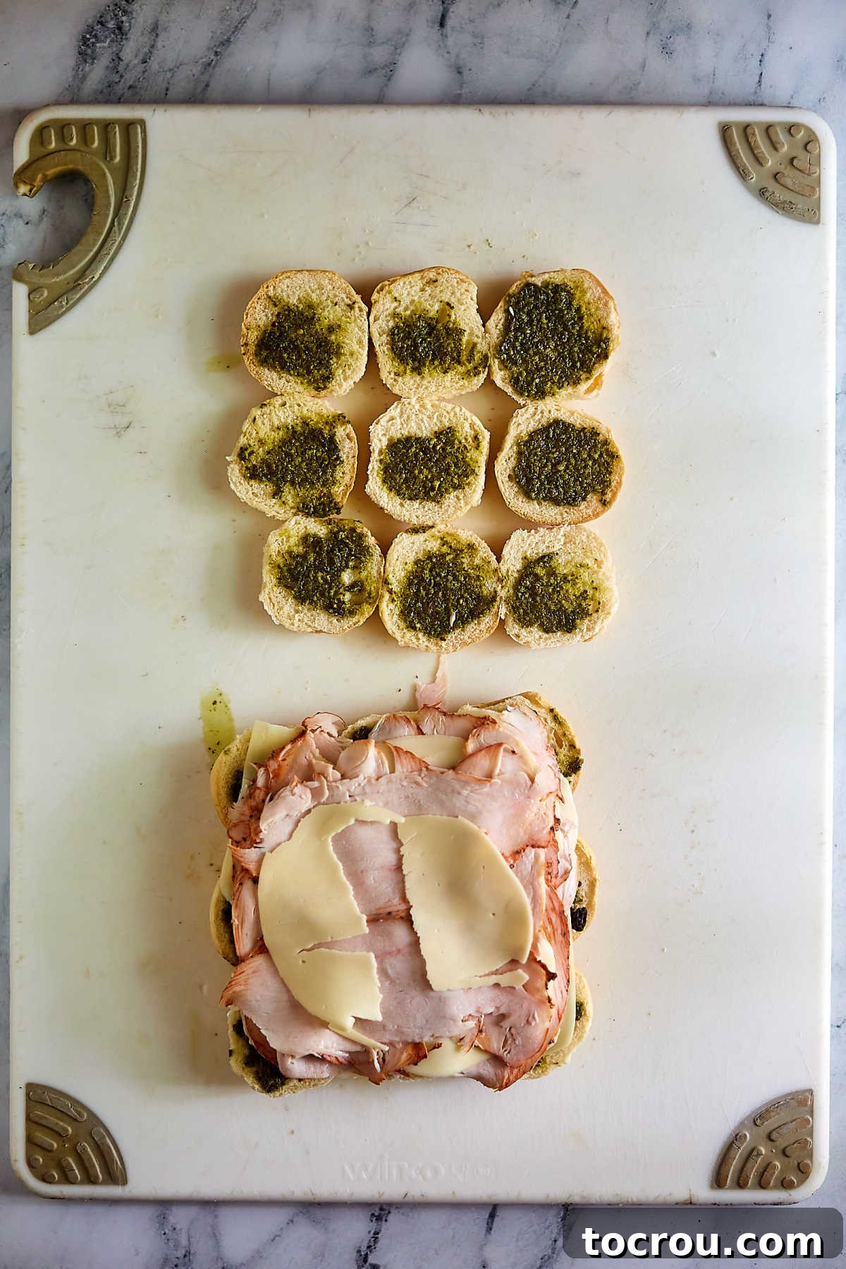 Half of the slider buns are being layered with tender turkey slices and additional cheese, building the flavorful foundation of the sandwiches.