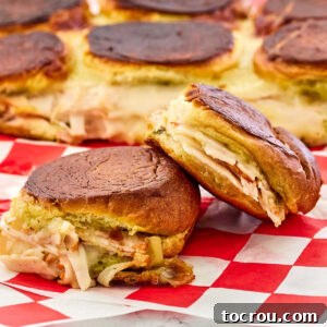 Grilled cheese sliders with toasted buns, savory turkey, vibrant pesto, sweet cranberries, and gooey melted cheese, presented ready to eat.