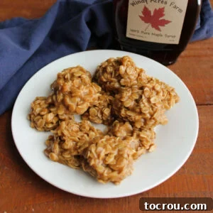 Plate of no bake maple cookies with oatmeal next to a bottle of pure maple syrup.