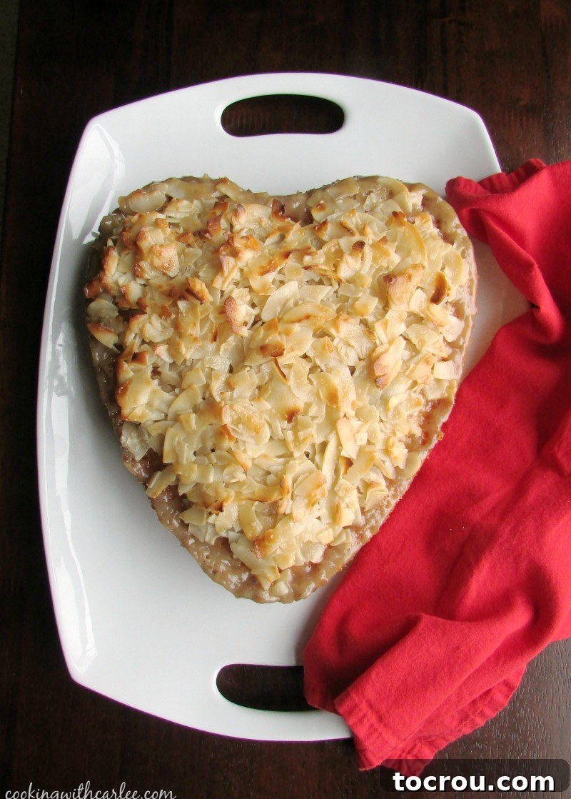 A close-up of the rich Greek coconut cake, showing the abundance of coconut and the gleaming, syrup-soaked surface, topped with golden flakes.