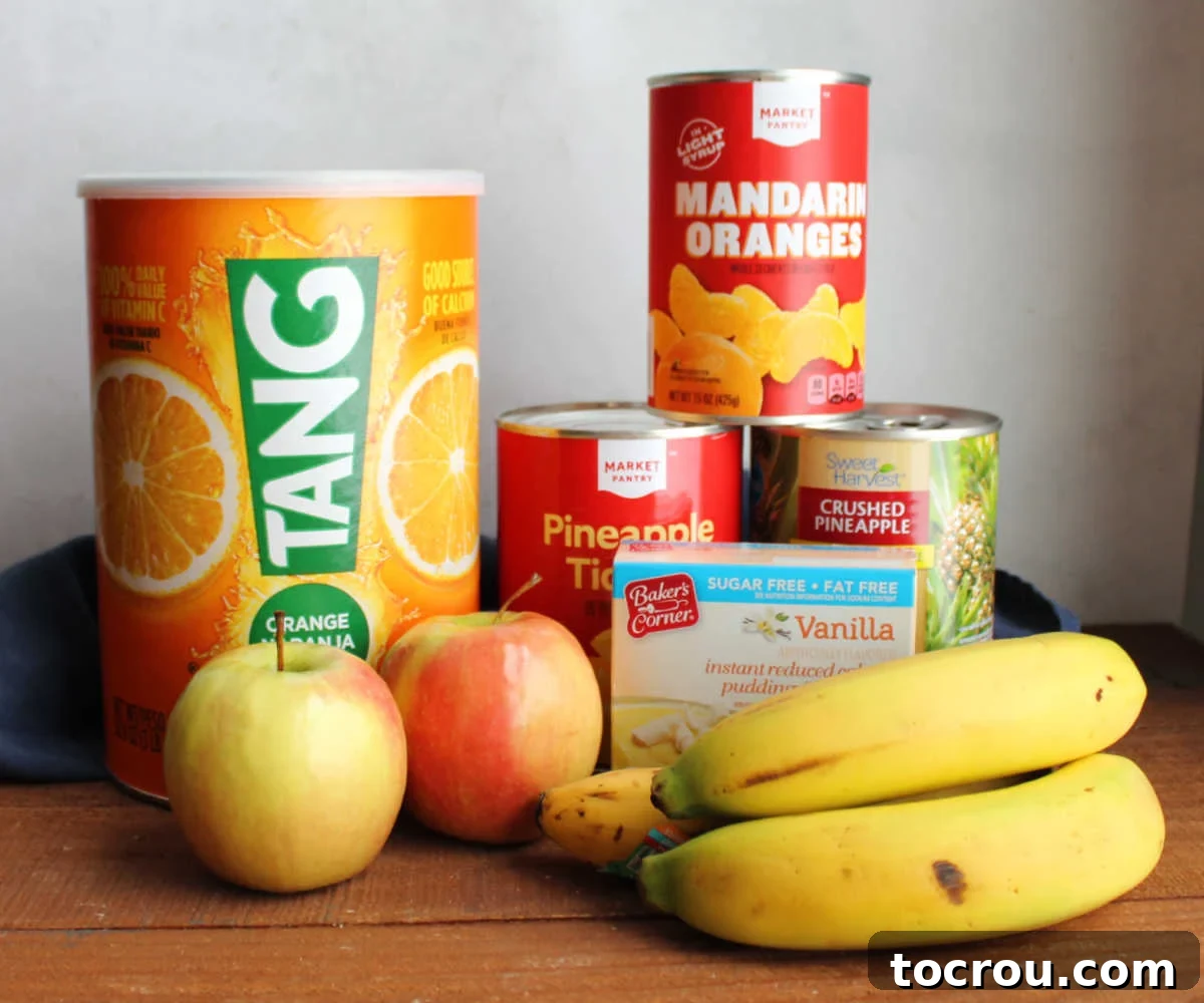 Zesty Fruit Medley 3 Ingredients including Tang powder, apples, bananas, cans of pineapple and oranges and a box of vanilla instant pudding mix ready to be made into a vintage Tang fruit salad.