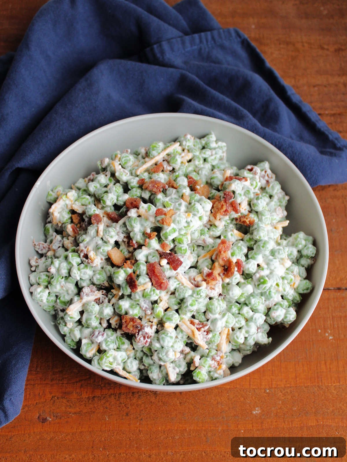 Pea salad topped with extra chopped bacon, ready to be served.