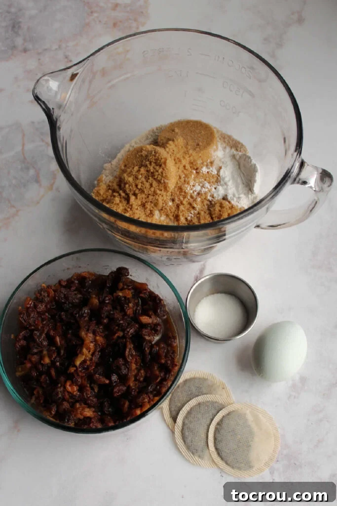 Irish Fruit Tea Loaf 3 Irish tea brack ingredients including bowl of flour and sugar, raisins and dates soaking in tea, tea bags, sugar and an egg ready to be made into batter.