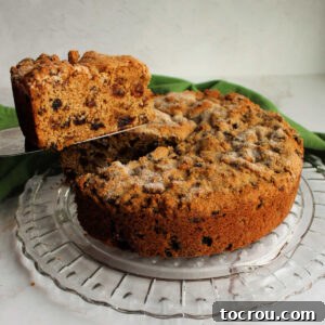 First slice of Irish tea brack being lifted out of round cakelike loaf, showing lots of fruit in the interior.