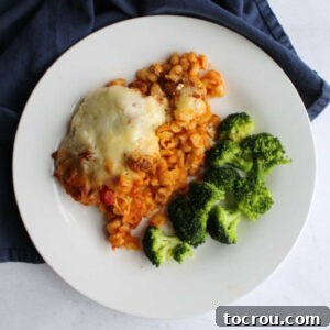 dinner plate with baked Italian style pasta casserole and broccoli. A delicious serving of cheesy pasta, perfect for a family meal.