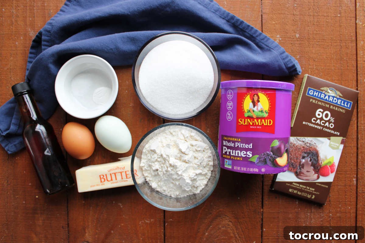 Ingredients including vanilla, eggs, butter, salt, baking powder, flour, sugar, prunes, and bittersweet chocolate ready to be made into prune brownies, laid out neatly for baking.