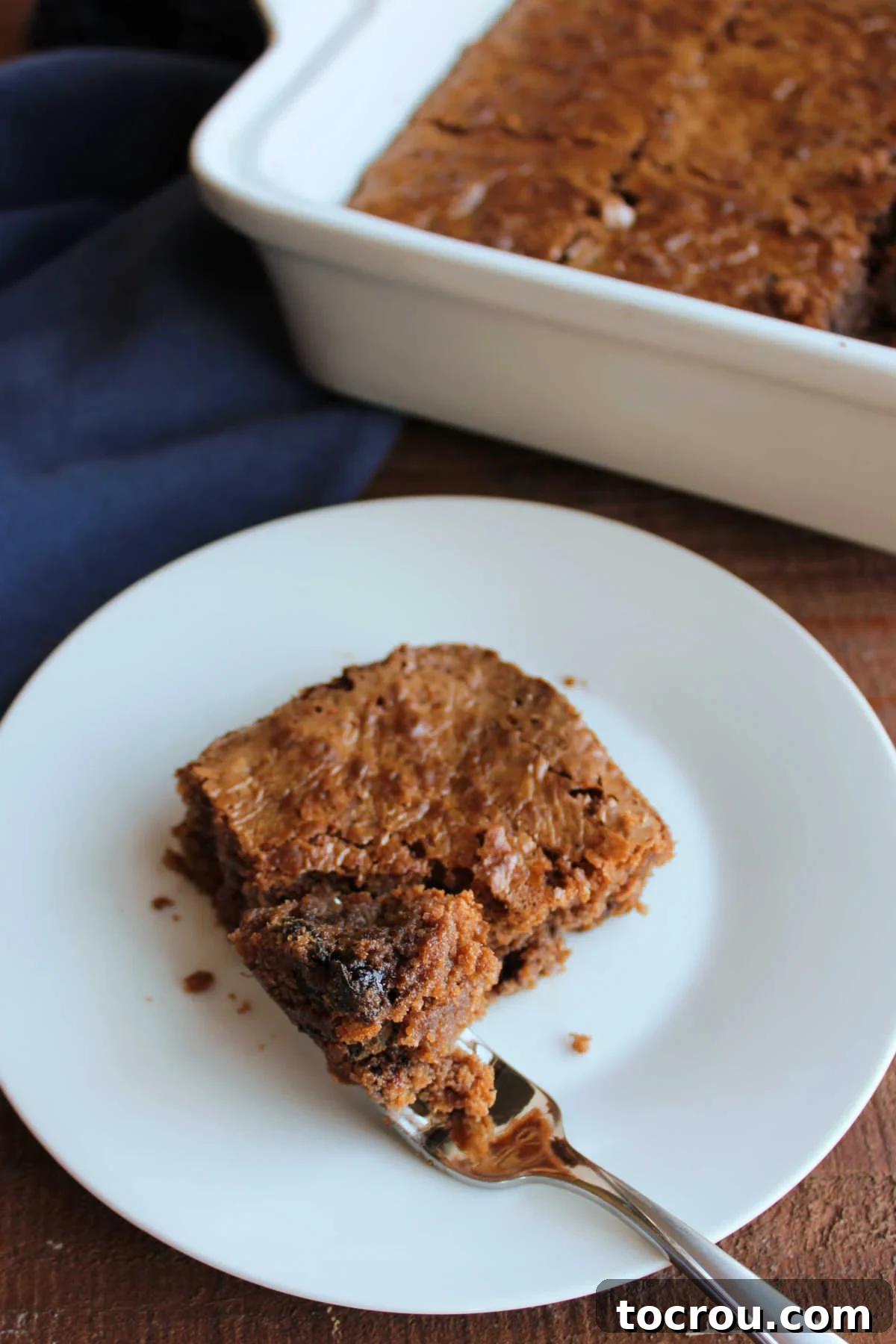 Bite of prune brownie on fork, ready to eat, with visible prune pieces and a moist, dark crumb.