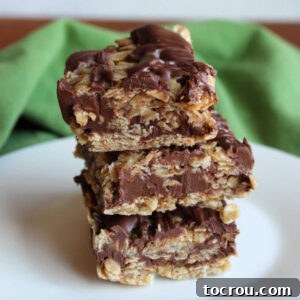 No bake oatmeal cookie bars with layers of oat mixture around a chocolate and peanut butter layer stacked on top of each other.