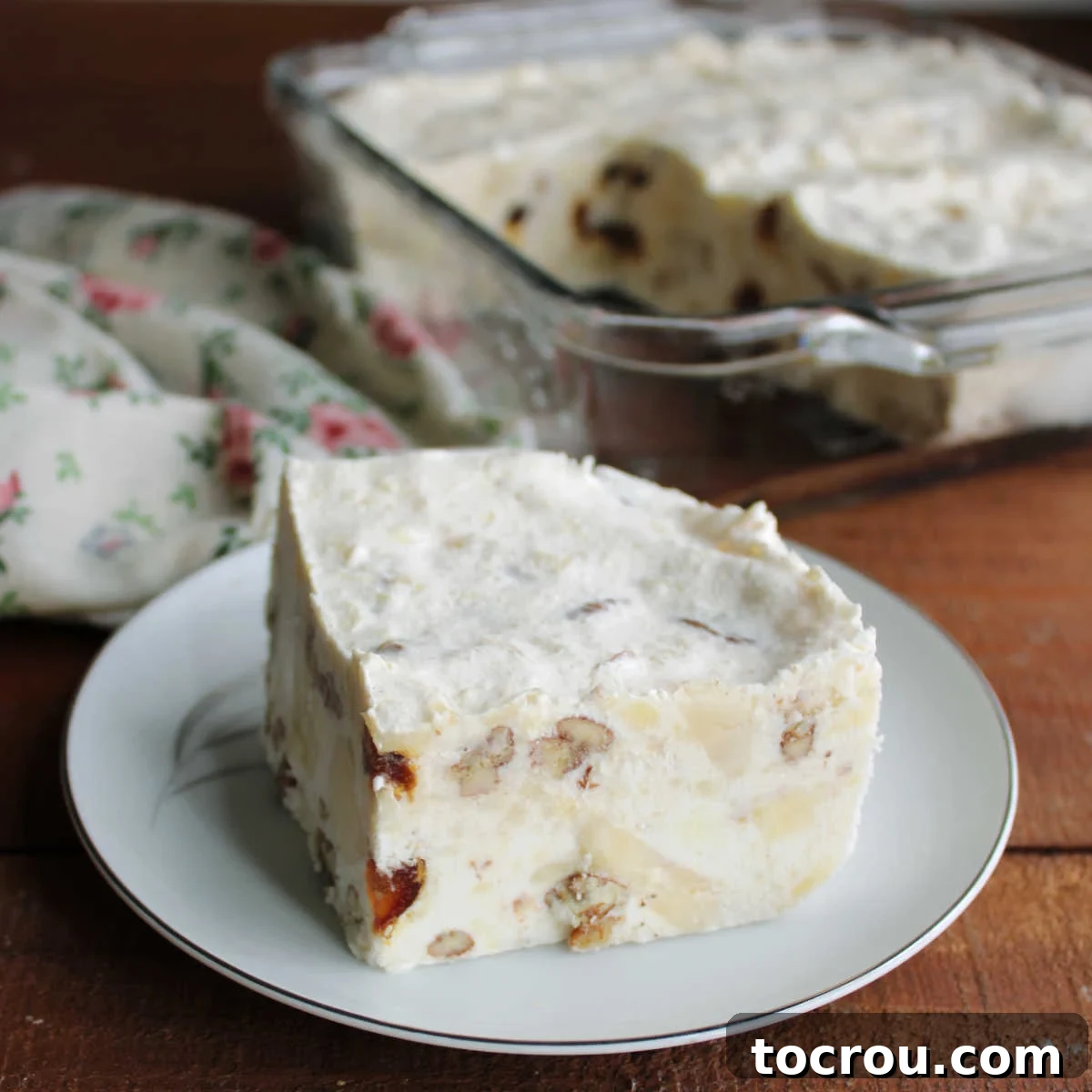 Square piece of frozen fruit salad with dates, bananas, pineapple, and pecans in a creamy base.