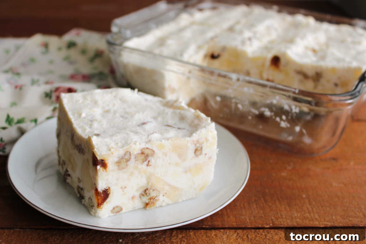 Piece of great-grandma's frozen date and cream cheese salad showing bits of fruits and nuts suspended in creamy frozen base.