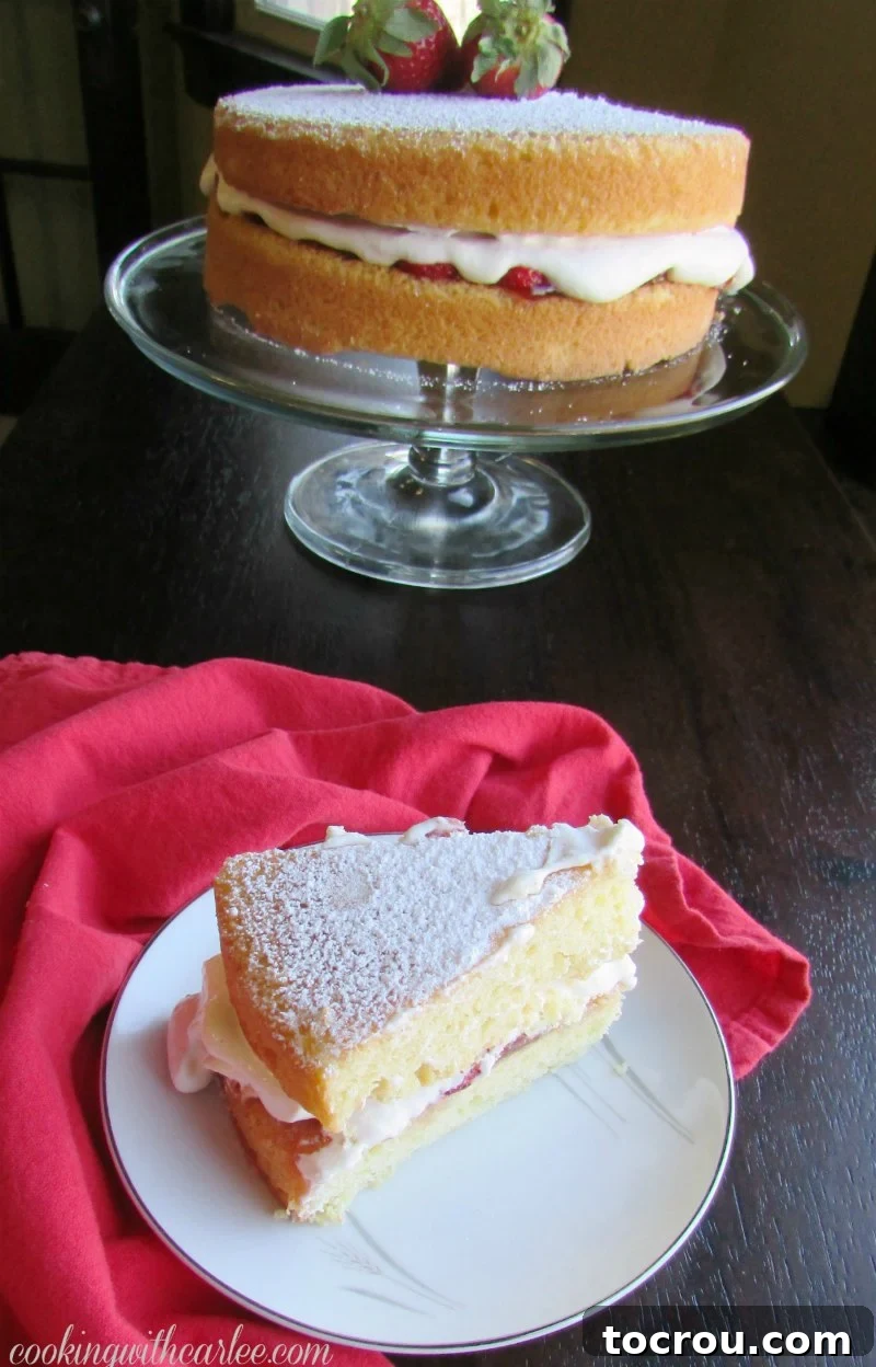 A delectable slice of Victoria Sponge Cake on a plate, showcasing its fluffy layers, rich strawberry jam, and light chantilly cream. The remaining cake sits elegantly in the background.