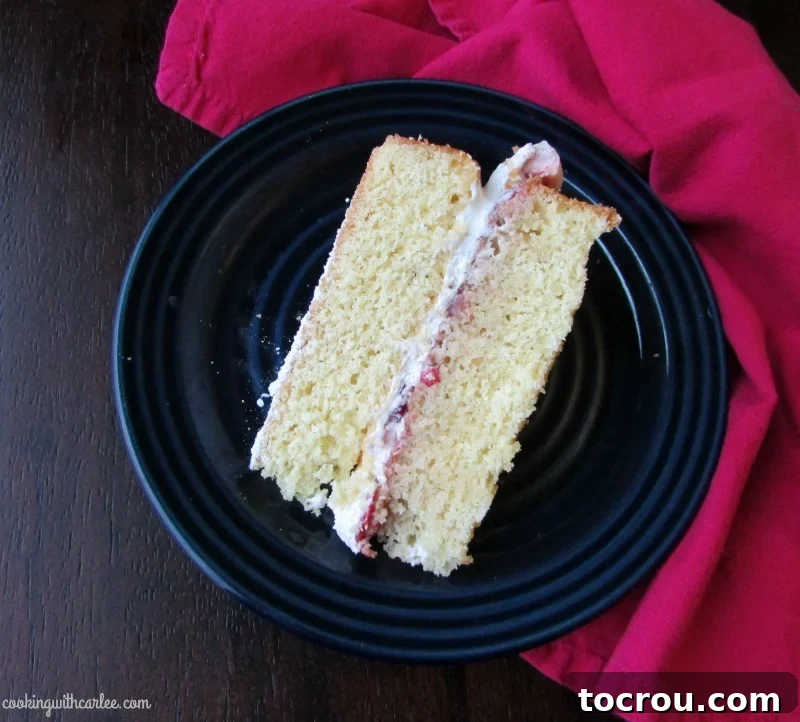 A beautifully decorated whole Victoria Sponge Cake filled with vibrant strawberries and luscious whipped cream, ready to be served.