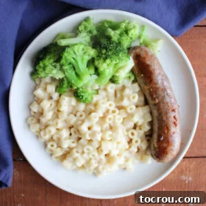 Dinner plate with an Italian sausage link, broccoli, and a generous helping of creamy parmesan ditalini pasta.