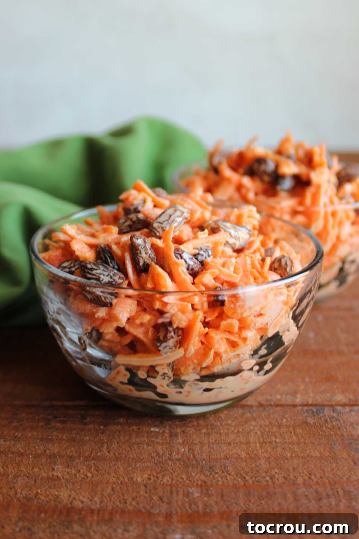 Heirloom Carrot Raisin Salad 6 A beautifully presented bowl of carrot raisin salad, perfectly mixed and chilled, with a garnish of a few fresh carrot shreds, signifying it's ready to be enjoyed as a refreshing side dish.