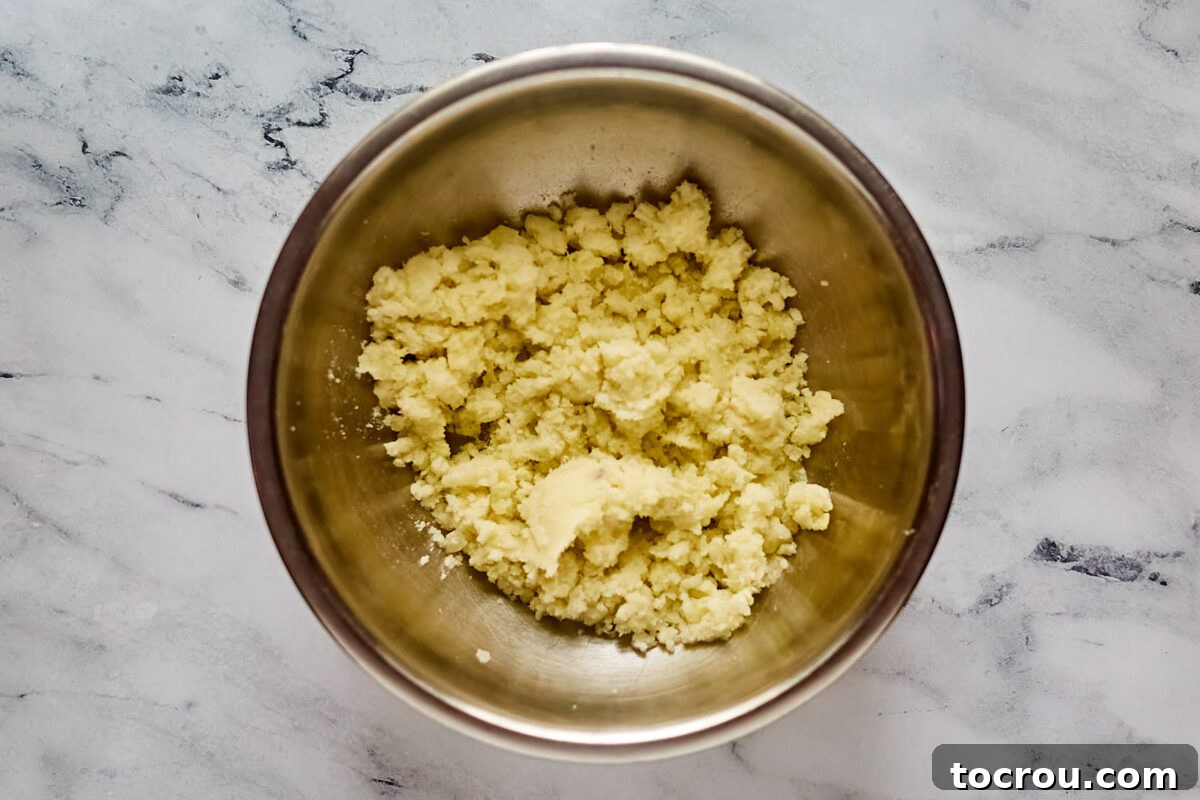 Large mixing bowl with the center of a large baked potato mashed up inside.