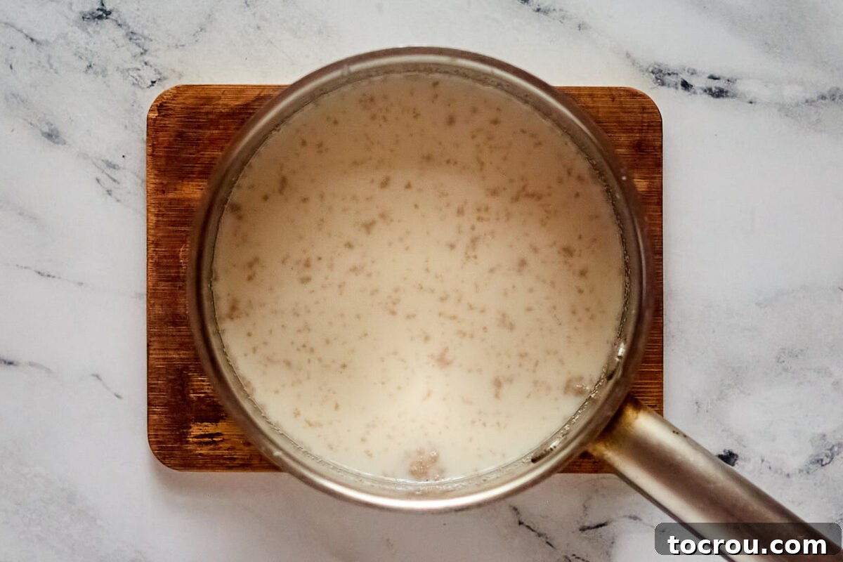 Saucepan with warm milk, sugar, and yeast inside.