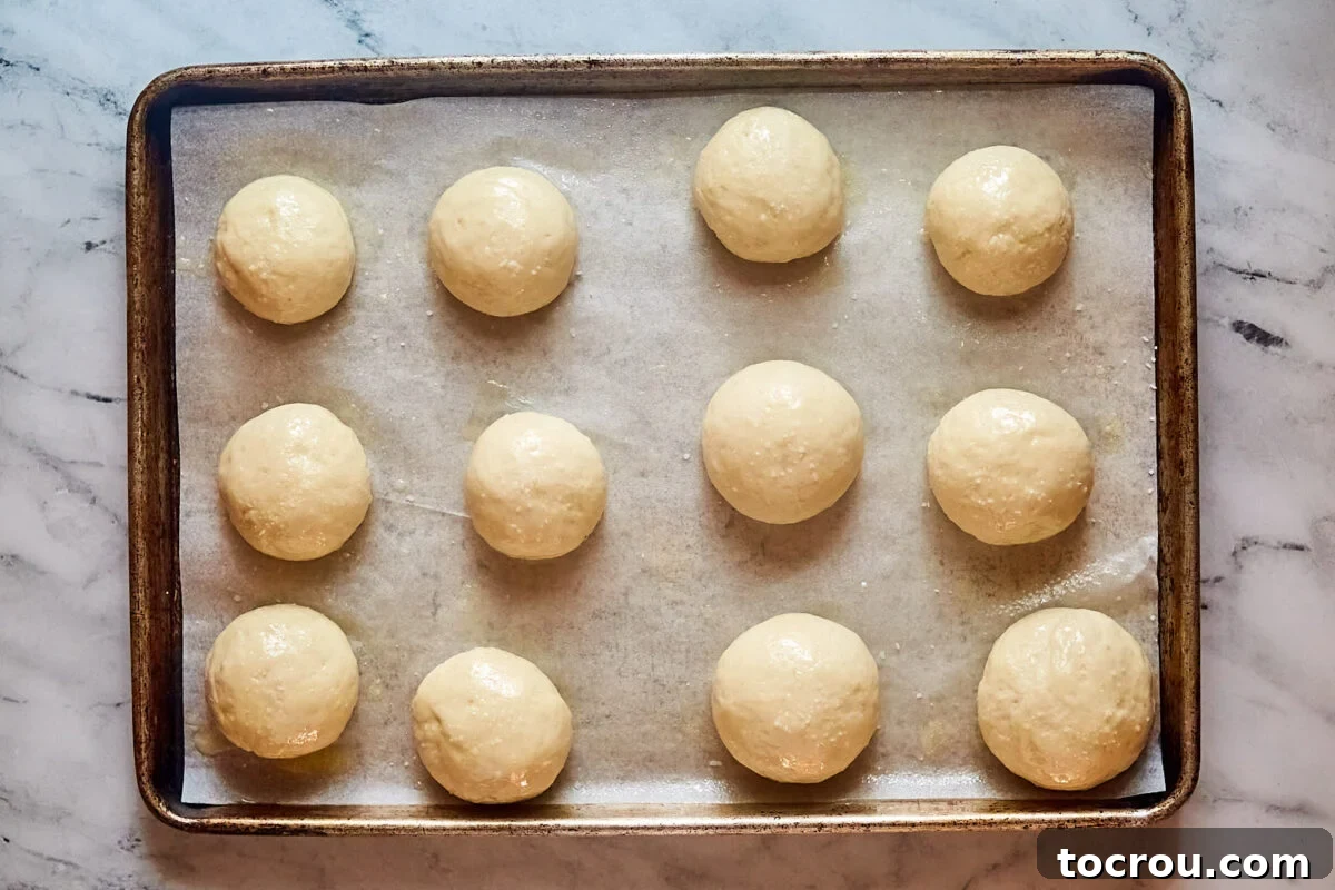 Proofed balls of potato roll sough on pan, ready to go in the oven. 
