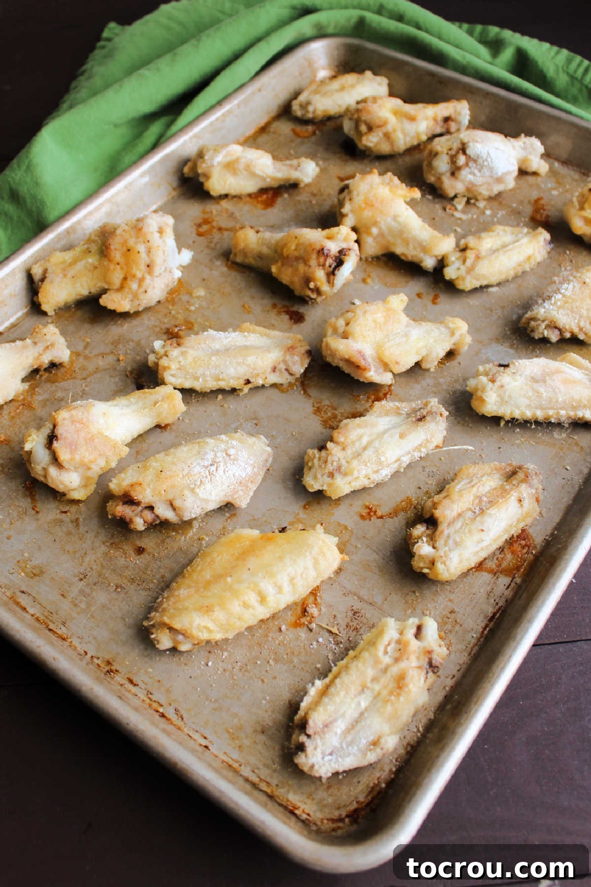 Wings baked to a perfect golden crisp. Crispy baked chicken wings, golden brown and glistening, fresh out of the oven before saucing.