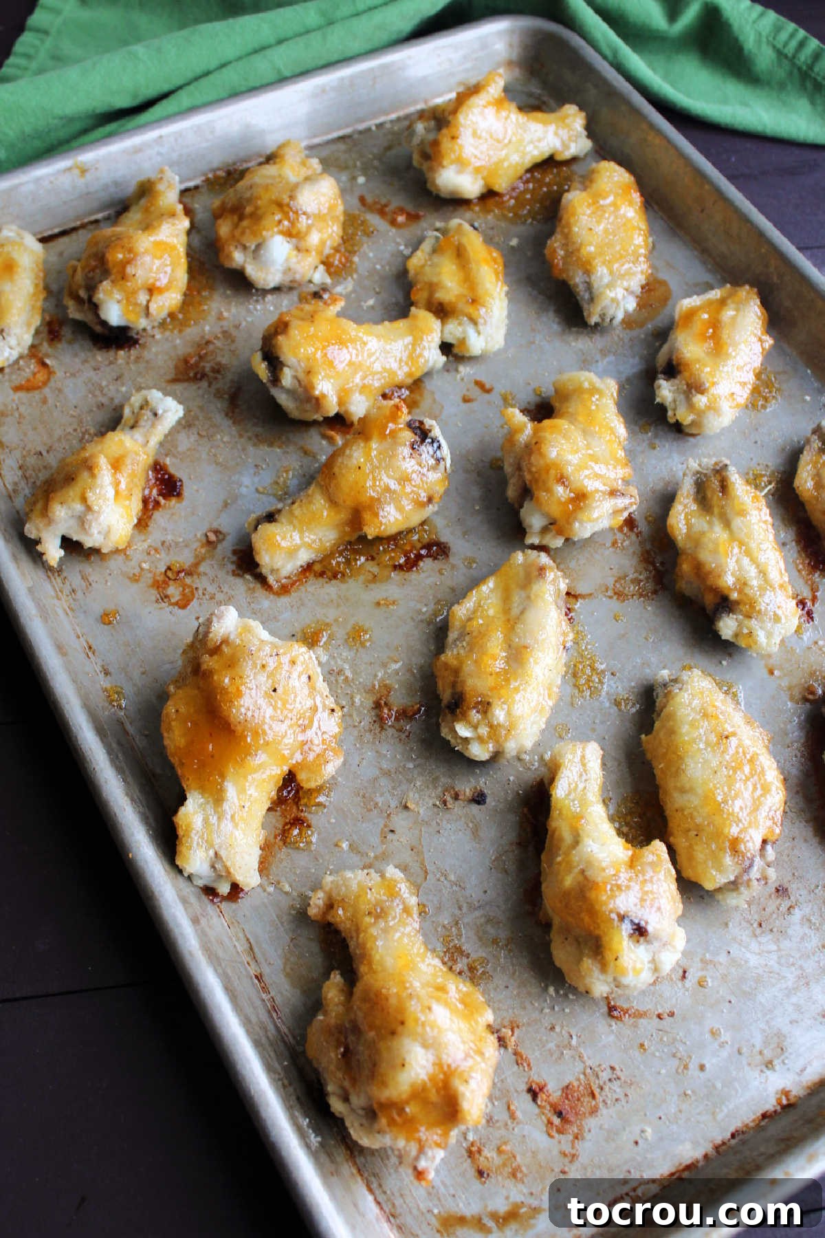 Wings coated in delicious peach habanero sauce. Baked chicken wings coated in a vibrant peach habanero sauce, arranged on a baking sheet, ready for a final bake.