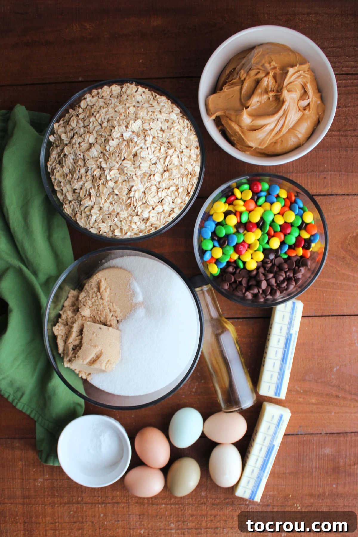 Essential Monster Cookie Ingredients Ingredients including peanut butter, oatmeal, sugar, brown sugar, eggs, butter, vanilla, baking soda, chocolate chips, and M&Ms, ready to be made into monster cookies.
