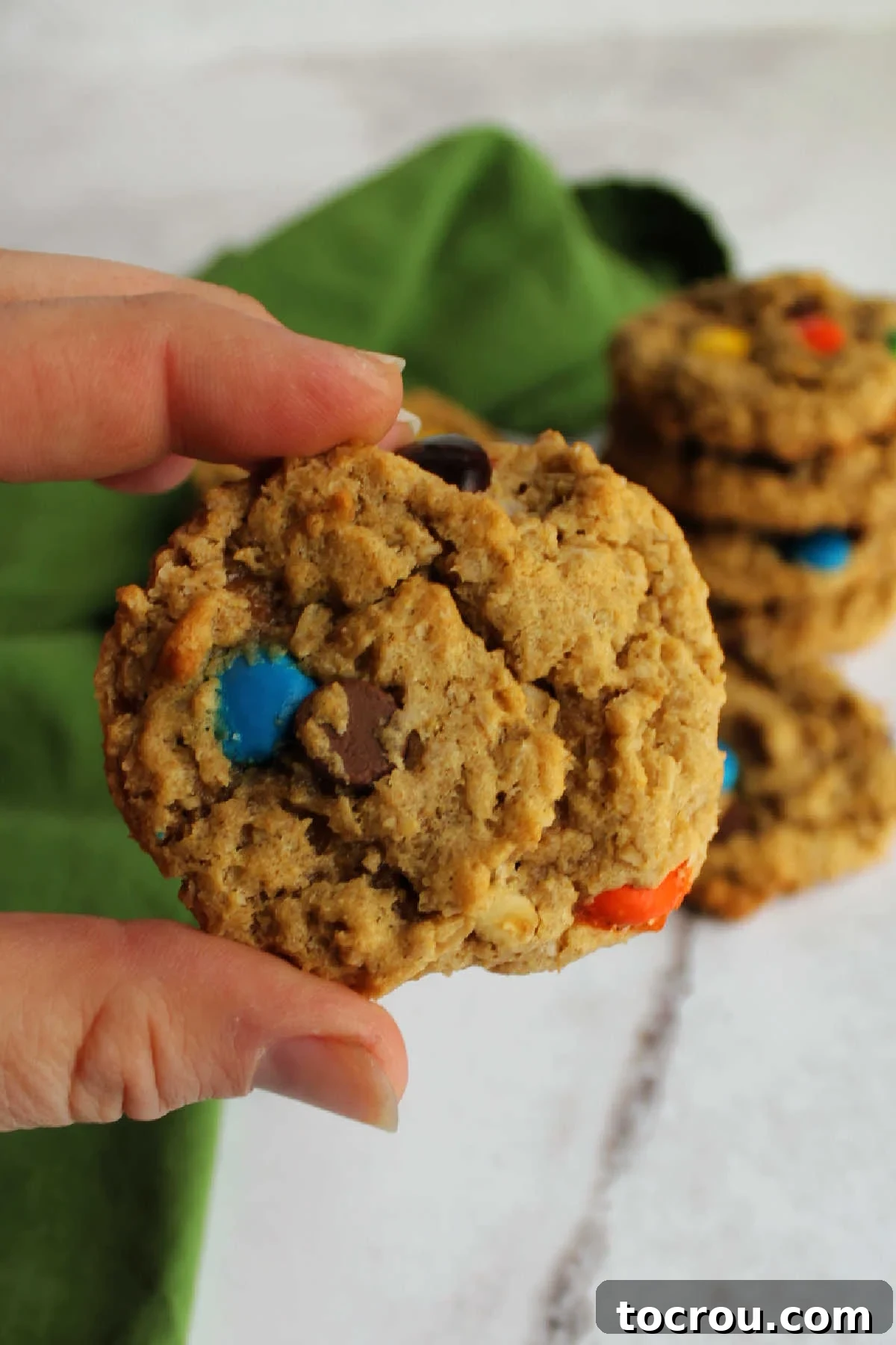 Enjoying a Fresh Peanut Butter Monster Cookie Hand holding a freshly baked peanut butter monster cookie.