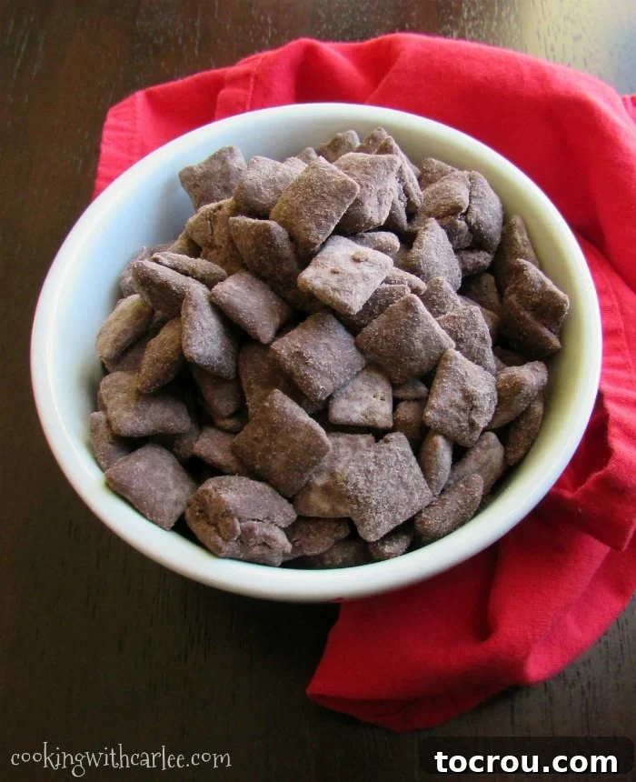 A delightful bowl of brownie batter puppy chow, featuring crispy cereal generously coated in a decadent chocolate and peanut butter brownie batter, ready for a satisfying snack break.