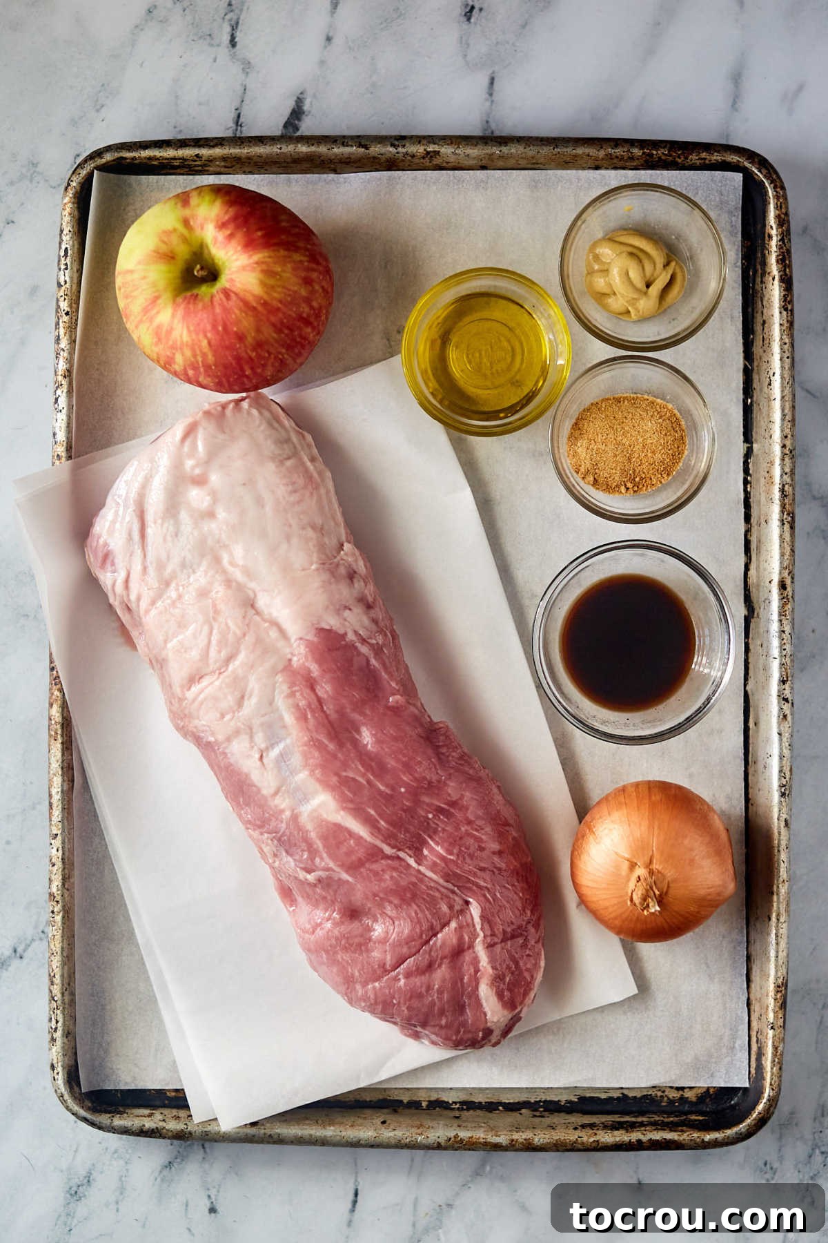 Fresh Ingredients for Stuffed Pork Loin Ingredients including a piece of pork loin, apple, onion, balsamic vinegar, mustard, and garlic ready to be made into stuffed pork loin.