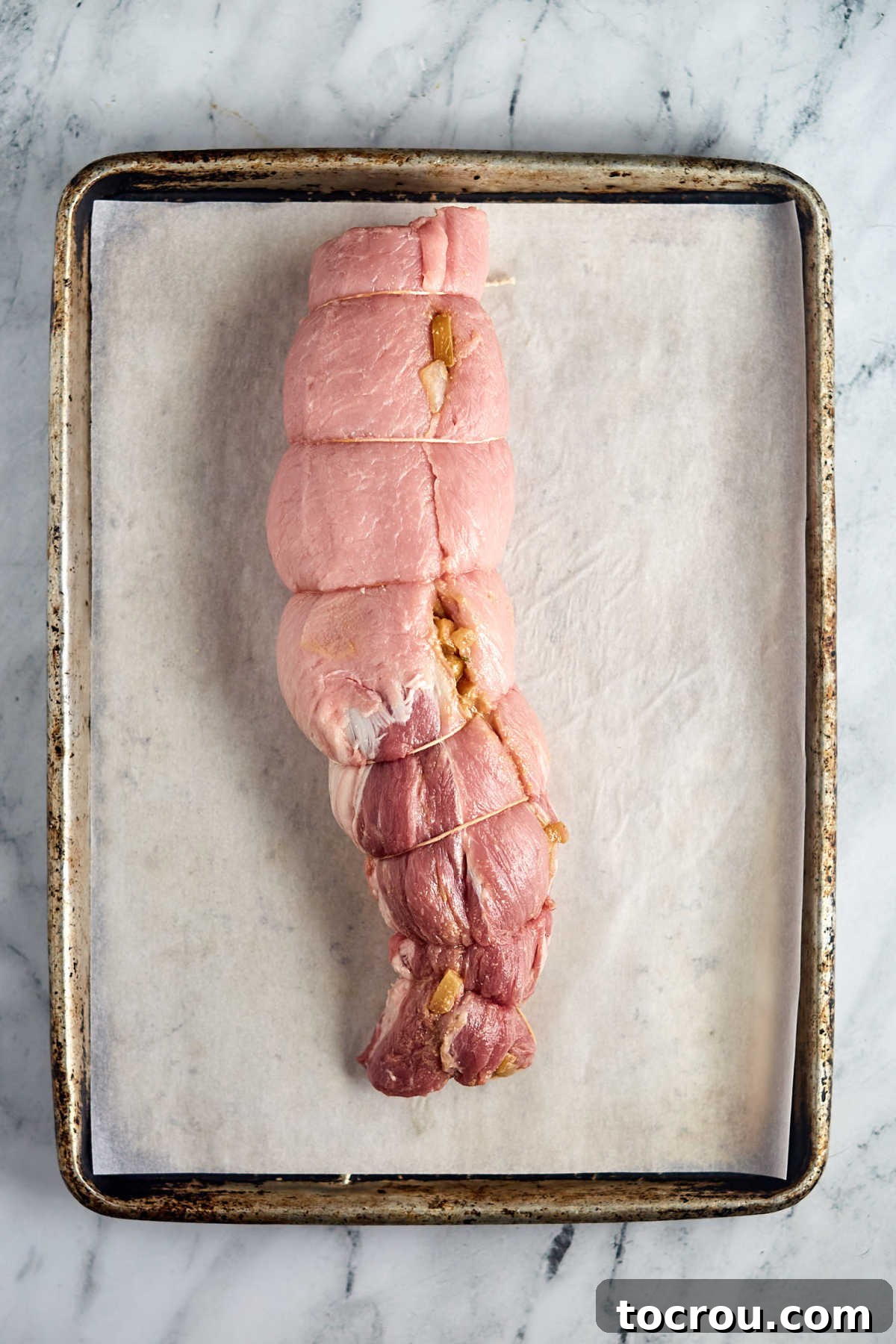 Rolled and Tied Pork Loin Pork loin rolled around the apple filling and secured with butcher's twine, ready to be cooked.