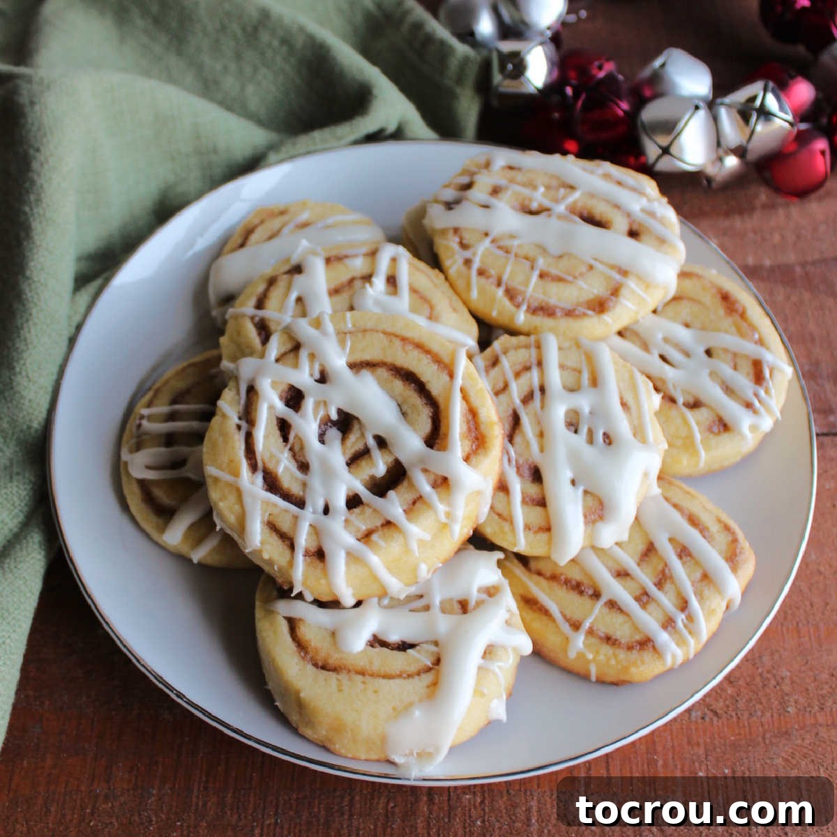 Plate of cinnamon roll cookies topped with cream cheese icing.