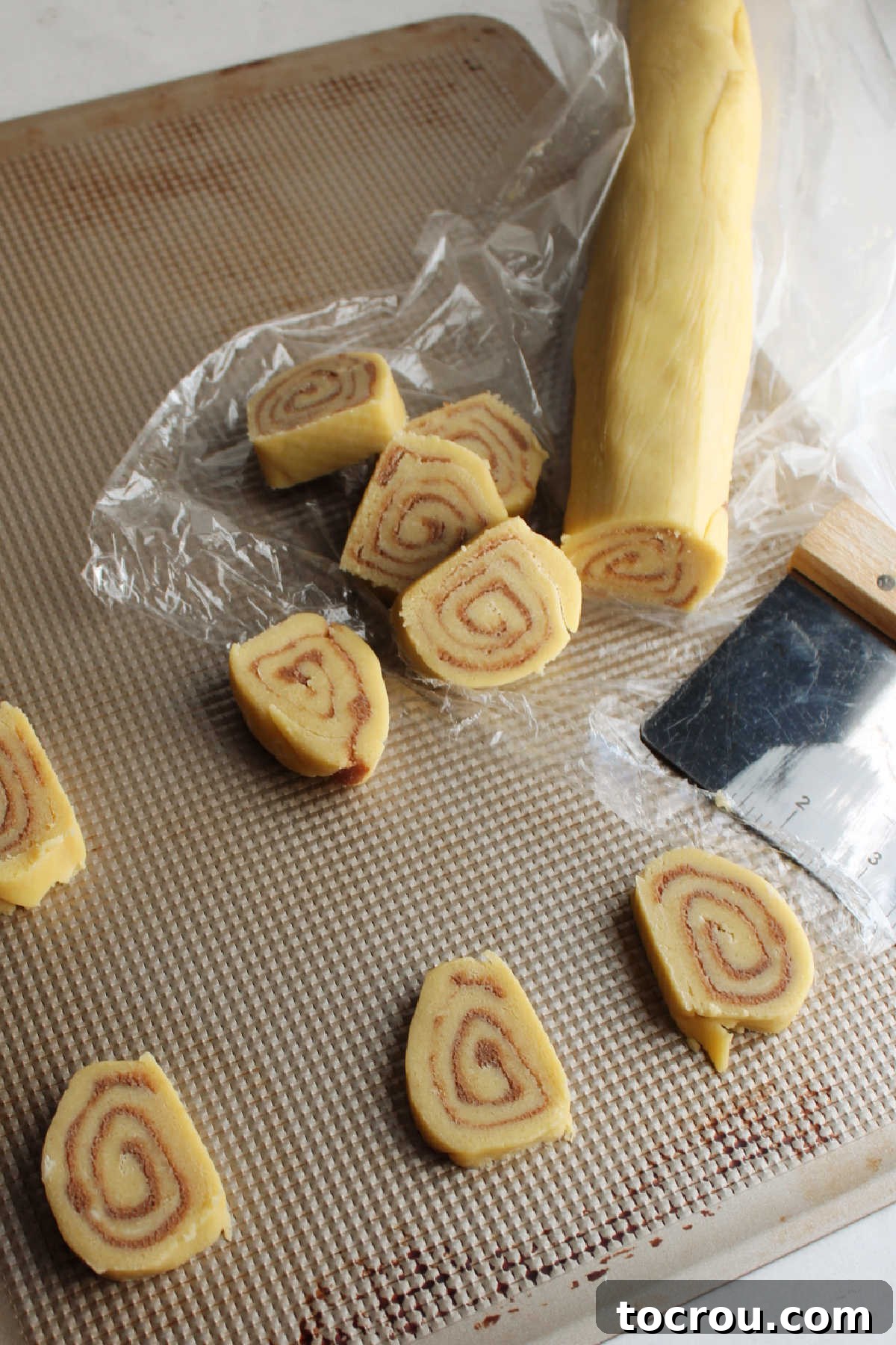 Slicing chilled log of cinnamon cookie dough and putting cookies on tray to bake.