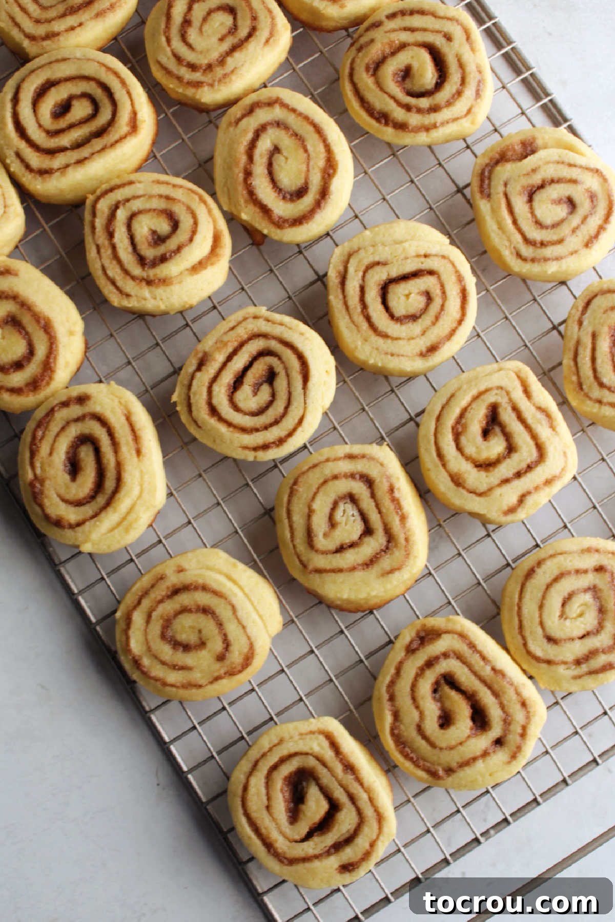 Freshly baked cinnamon roll cookies cooling on wire rack.