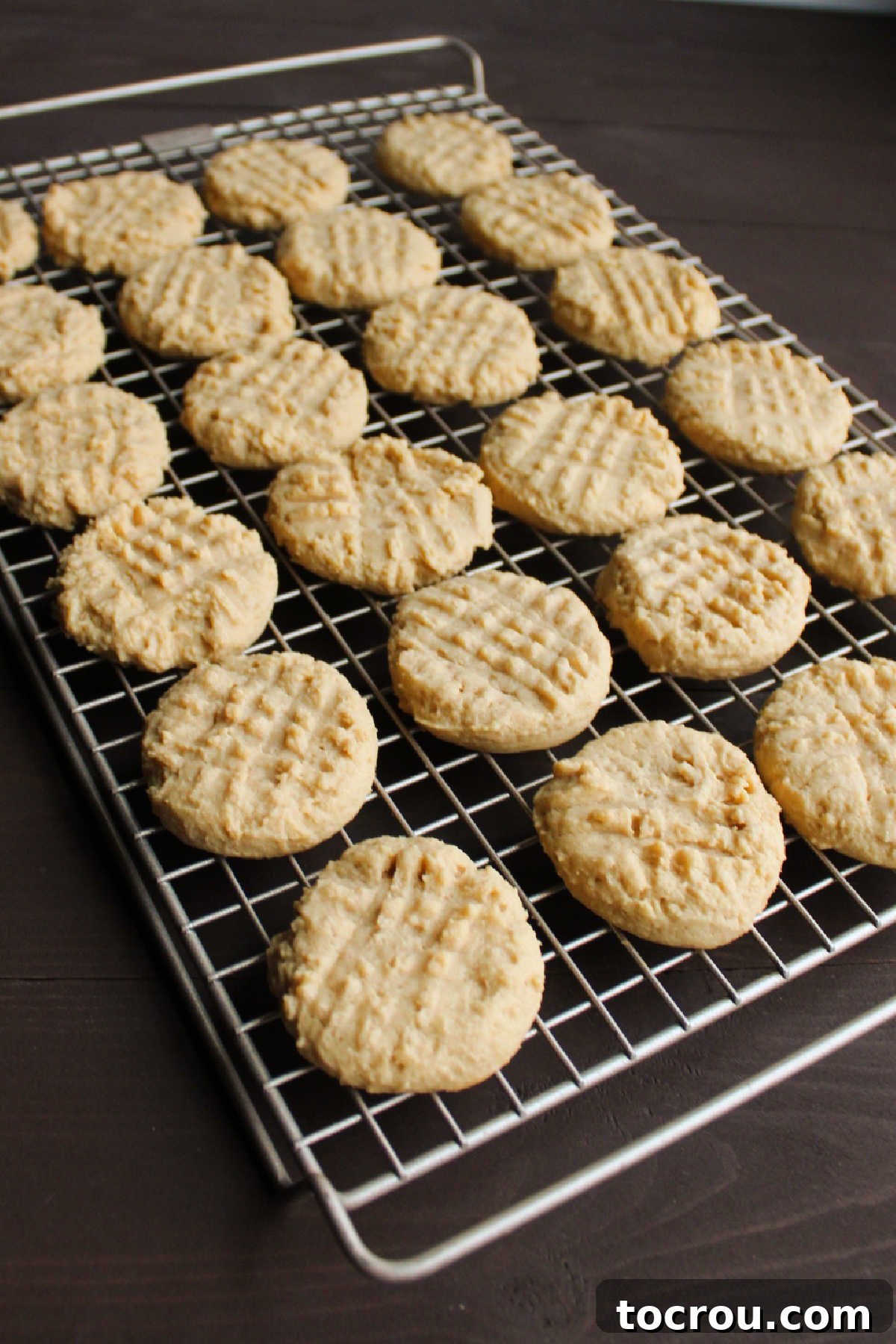 Grandma's Irresistible Peanut Butter Cookies 6 Cooling rack filled with freshly baked, soft peanut butter cookies, each adorned with the classic fork marks in a perfect crosshatch pattern.