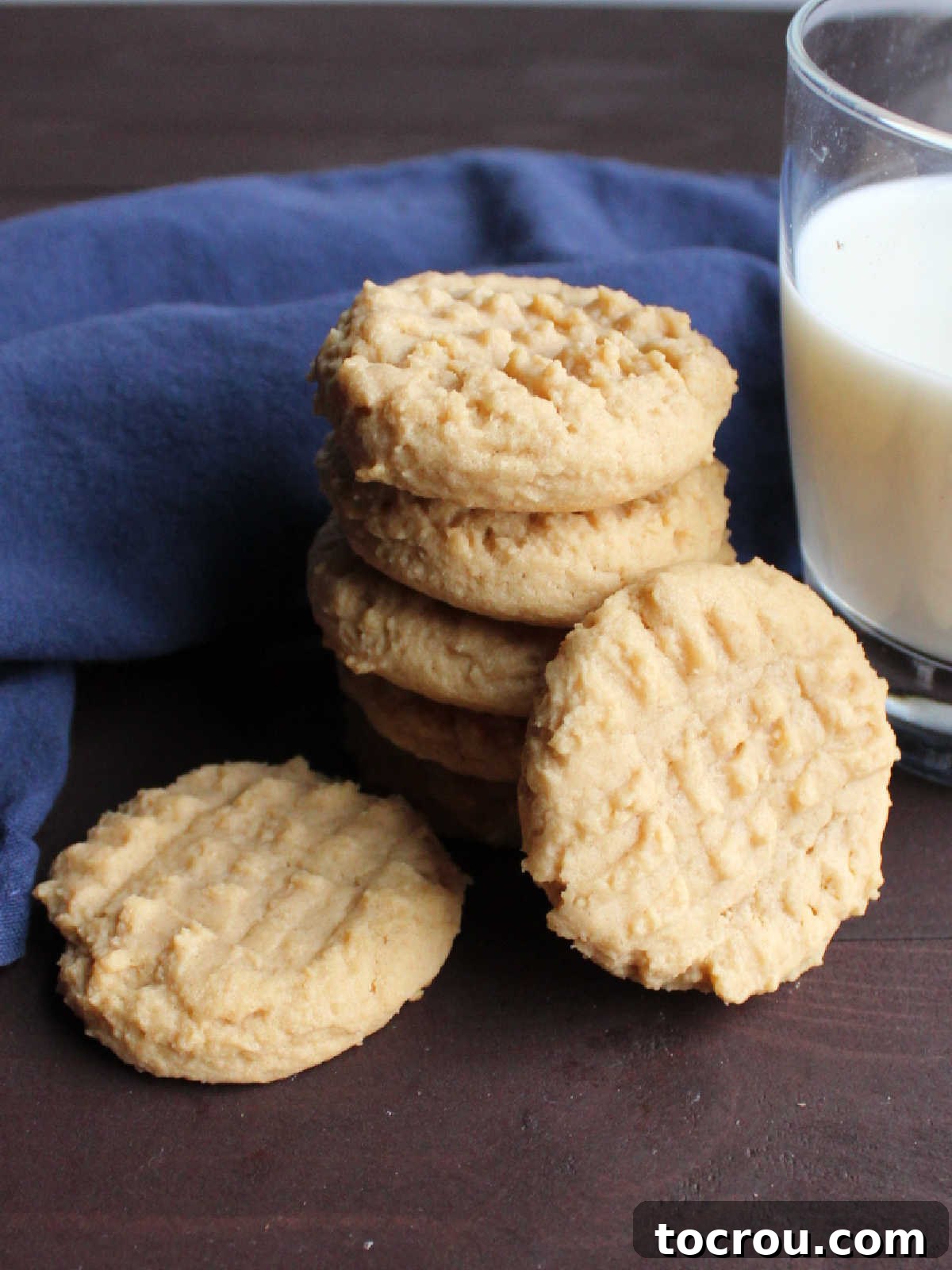 Grandma's Irresistible Peanut Butter Cookies 9 A delightful stack of grandma's homemade peanut butter cookies, perfectly paired with a refreshing glass of milk, creating a comforting and inviting scene.